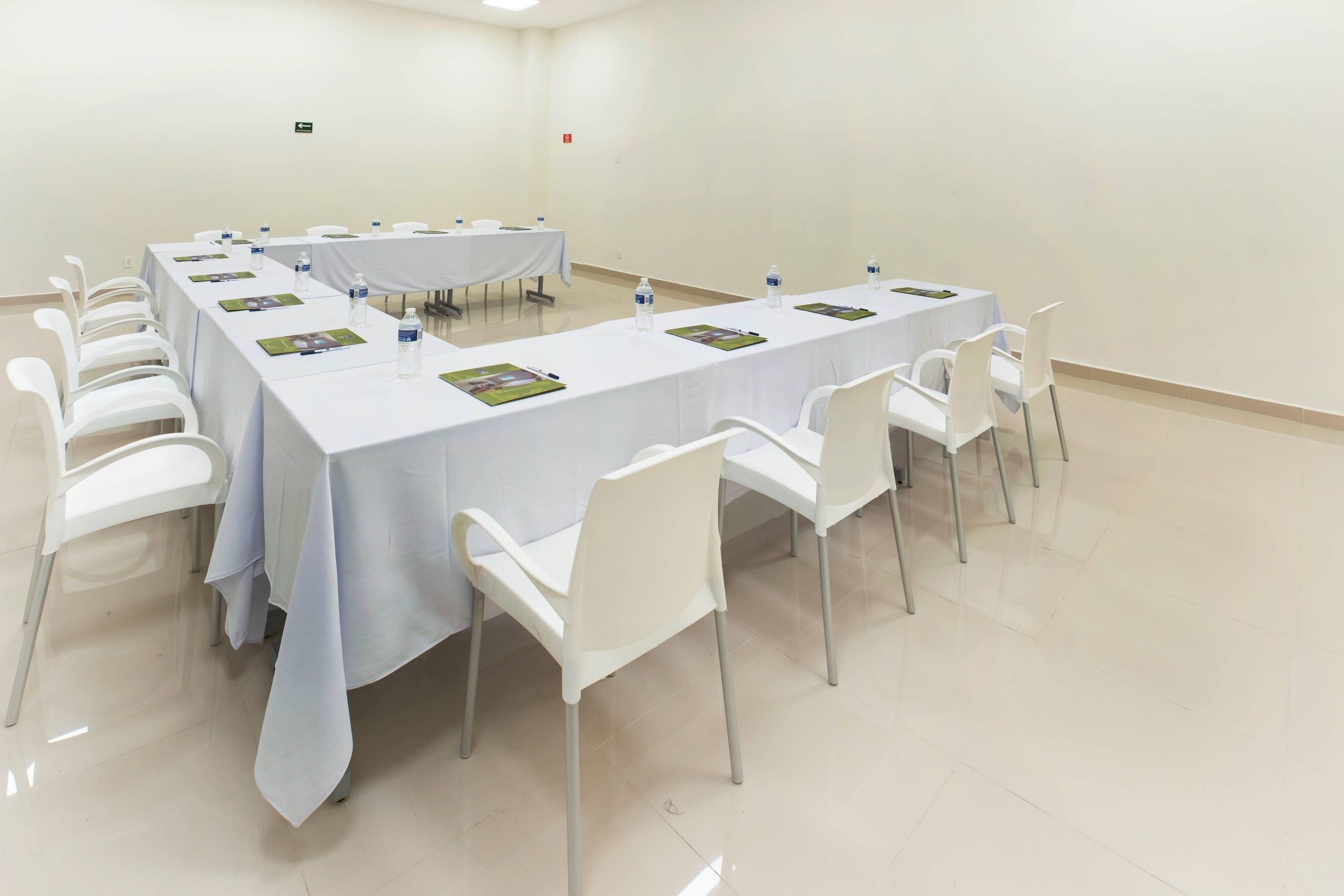 A conference room with a long table, white chairs, and water bottles.