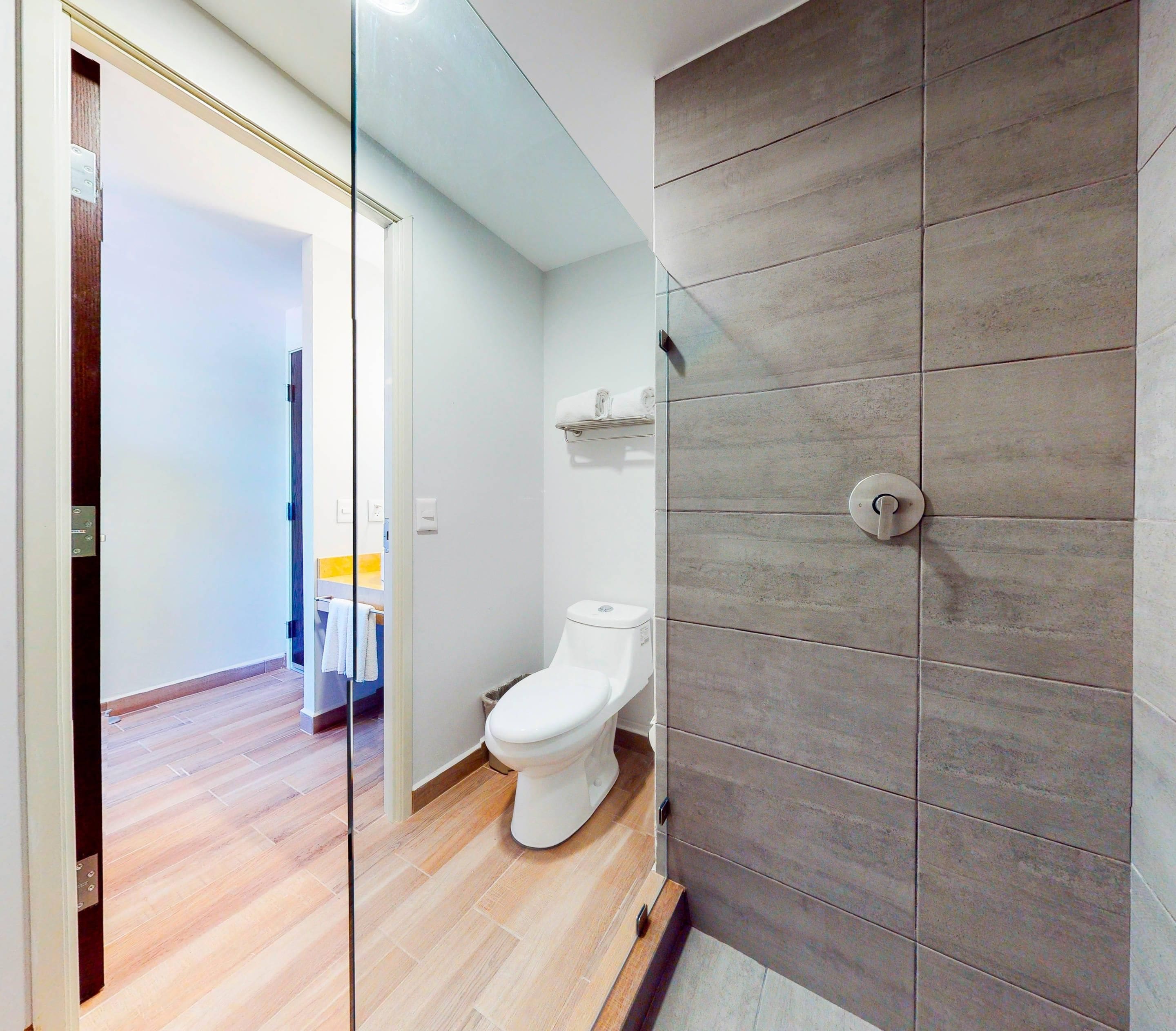 Un bagno moderno con il water, un porta asciugamani e una zona doccia.