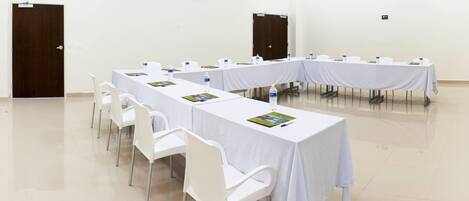A conference room with long tables, white chairs, and water bottles.