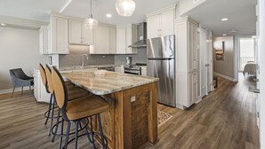 A modern kitchen with white cabinets, stainless steel appliances, and a wooden island with bar stools.
