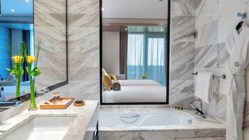 A modern bathroom with a large mirror, a bathtub, and a vanity with a sink.