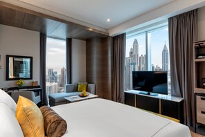 A modern hotel room with a large bed, a TV, and a city view.