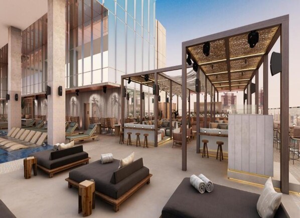A rooftop lounge with outdoor seating, a pool, and a bar area.