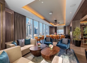 Un hall d’hôtel moderne doté d’un grand espace salon, d’un espace repas et de grandes fenêtres offrant une vue sur la ville.