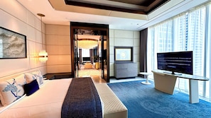 Ein Hotelzimmer mit Bett, Fernseher, Schreibtisch und Blick auf die Stadt.
