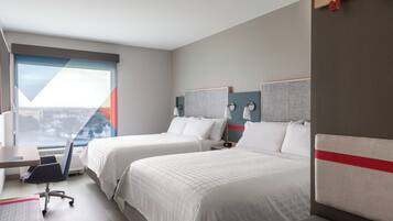 A hotel room with two beds, a desk, and a chair.