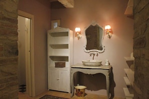 A bathroom with a white cabinet, a sink with a mirror above it, and two wall-mounted lights. - Private Room in small medieval borgo (Colle di Val d'Elsa)