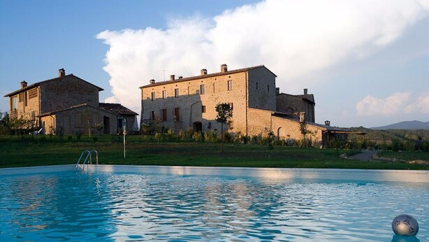 A swimming pool with a clear view of a large stone building in the background. - Private Room in small medieval borgo (Colle di Val d'Elsa)