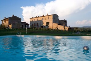 Une piscine offrant une vue dégagée sur un grand bâtiment en pierre situé au fond.