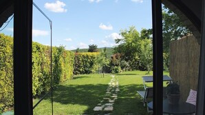 A view through an arched doorway into a garden with a stone path, a table, and chairs. - Private Room in small medieval borgo (Colle di Val d'Elsa)