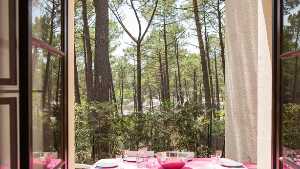 Zona pranzo con tavoli apparecchiati per quattro, affacciata su una vista boschiva.
