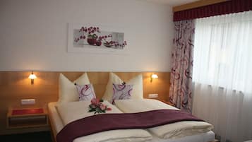 A neatly made bed with a floral arrangement, two bedside lamps, and a framed artwork above the bed.