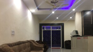 A reception area with a reception desk, a sofa, and a ceiling fan. - Hotel Duke Inn (Jhansi)