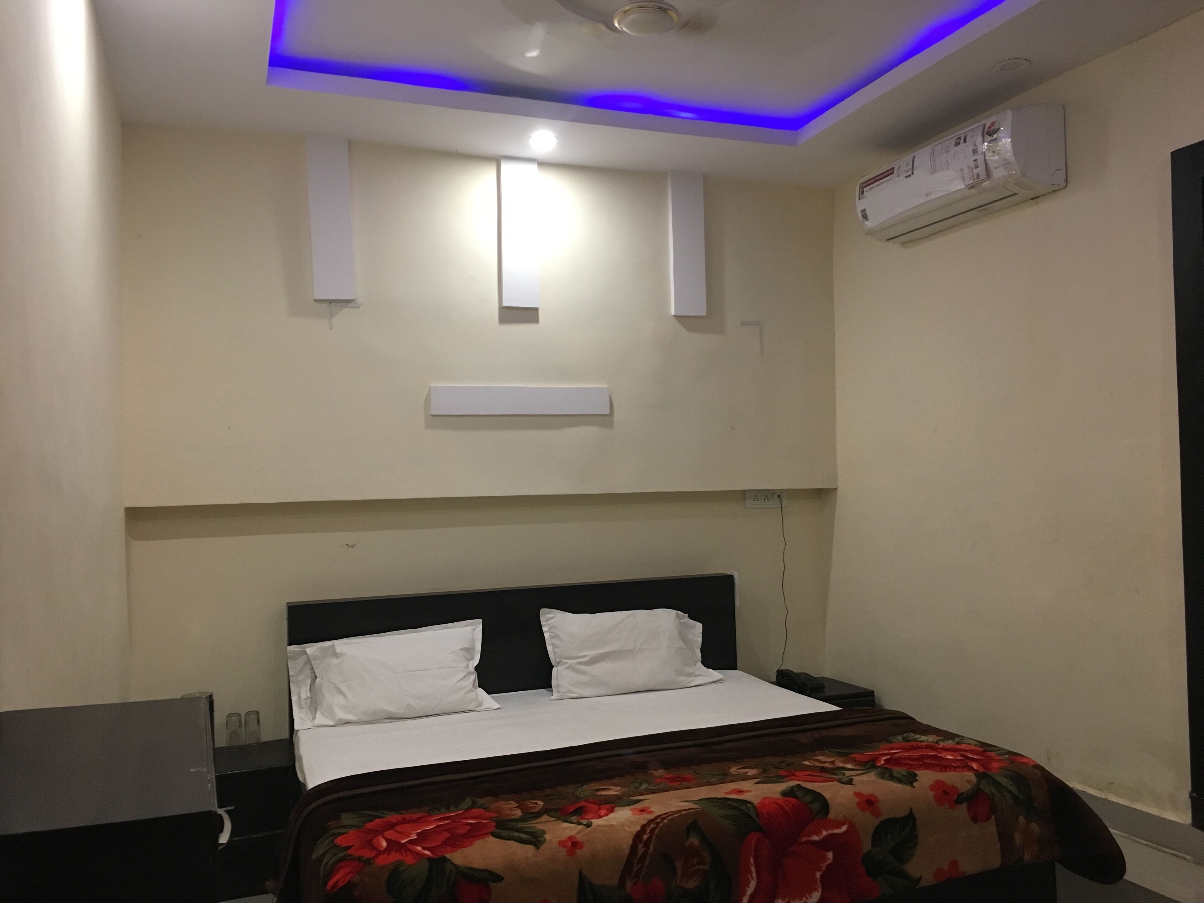Ein Hotelzimmer mit Bett, Nachttisch, Schreibtisch und Deckenleuchte.