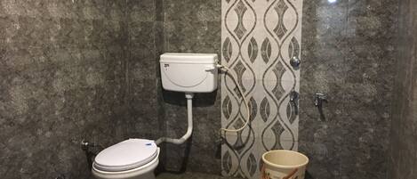 A bathroom with a toilet, a bidet, a red bucket, and a decorative bucket.