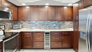 Una cocina moderna con armarios de madera, un refrigerador de acero inoxidable, un microondas y un tostador.