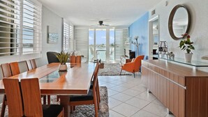 Una cocina moderna con comedor, que incluye una mesa y sillas de madera, una isla con encimera de vidrio y vistas amplias por grandes ventanales.