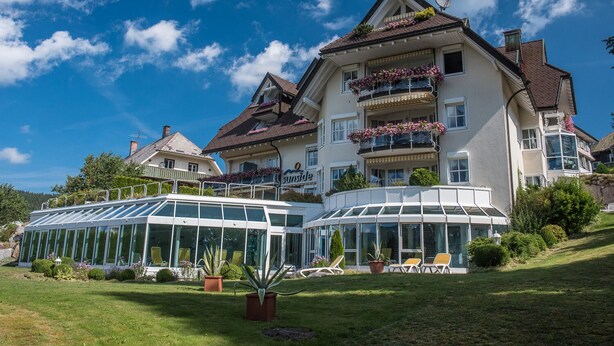 A large, multi-story hotel with a prominent glass conservatory and balconies with flower boxes.