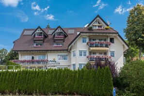 Un hôtel à plusieurs étages, doté de balcons, avec une enseigne indiquant « côté ensoleillé », et un ciel bleu dégagé.