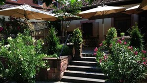 Un patio con pavimento de piedra, plantas en macetas y sombrillas.
