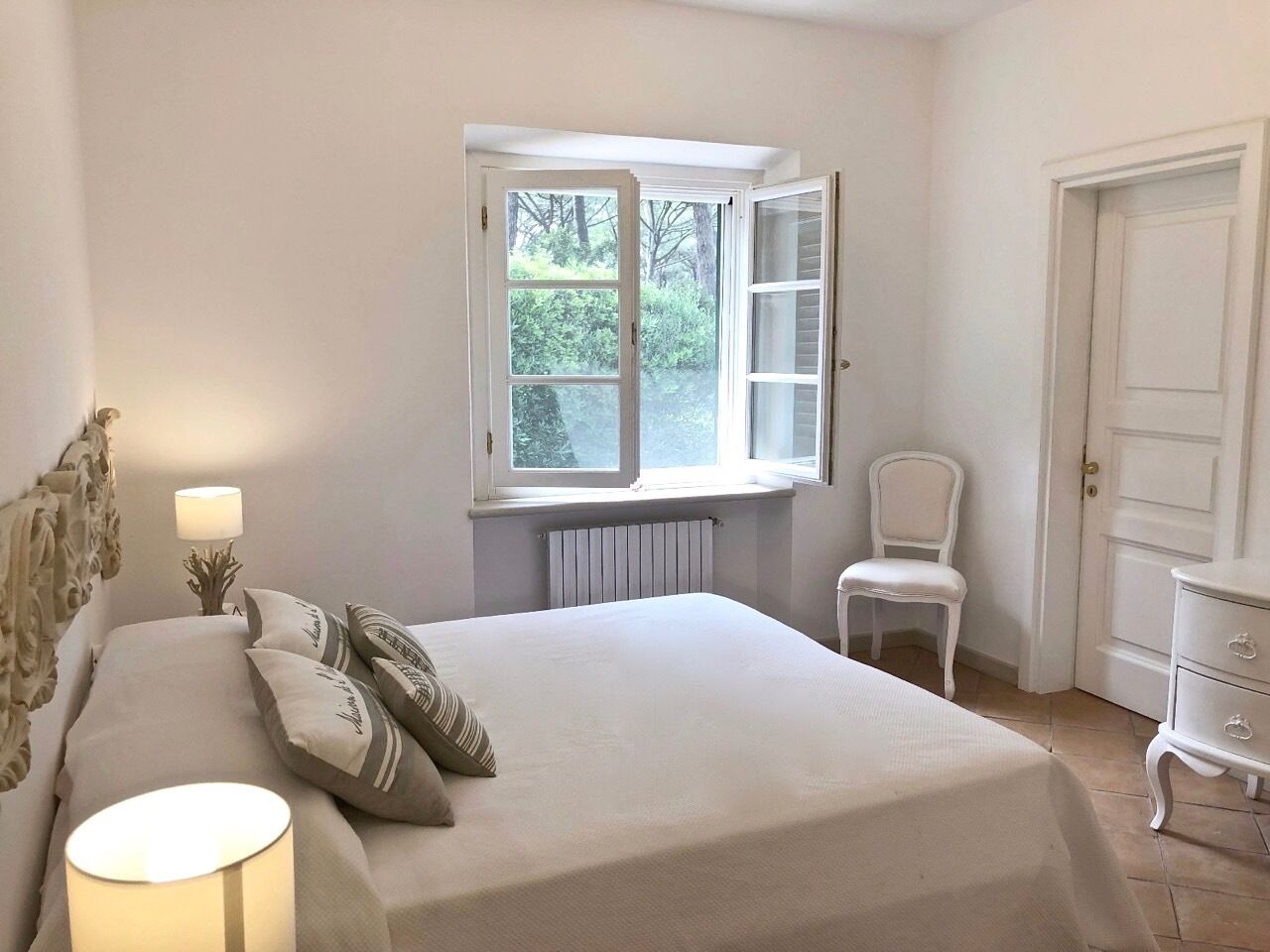 Un dormitorio con cama, ventana, silla y cómoda.