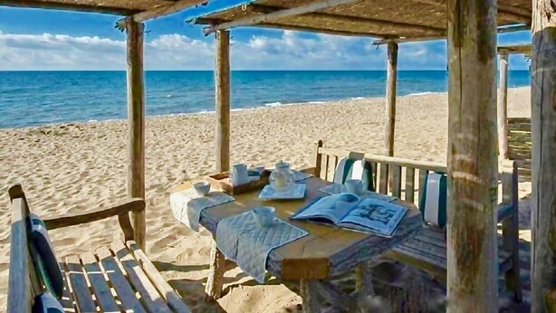 Eine hölzerne Strandhütte mit Tisch für zwei Personen mit Blick auf den Ozean.