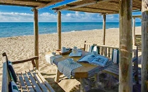 A wooden beach cabana with a table set for two, overlooking the ocean.