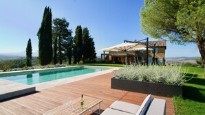 A modern house with a swimming pool, wooden deck, and outdoor seating area.