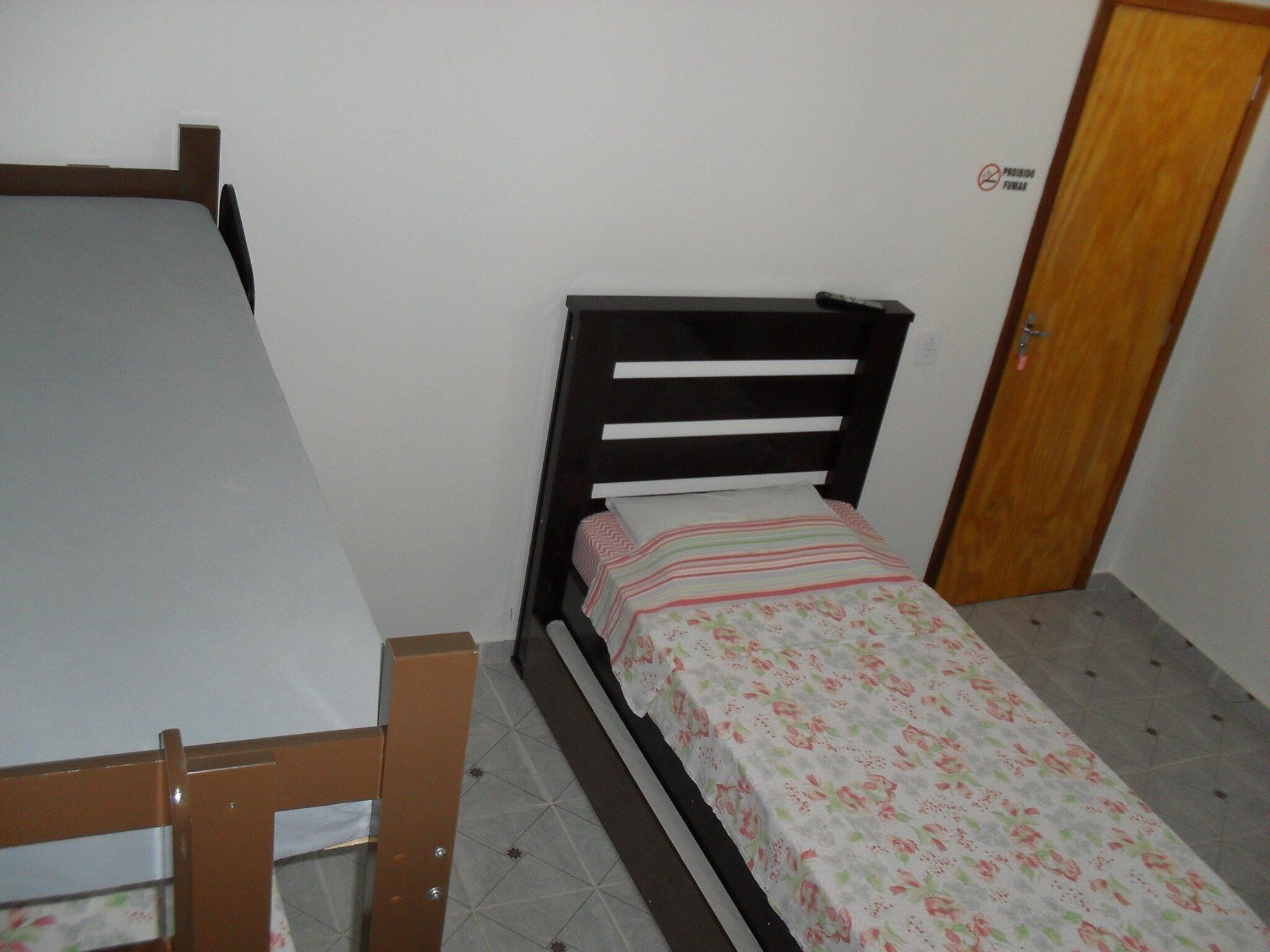 A small, single-bed room with a wooden headboard and a floral bedspread.