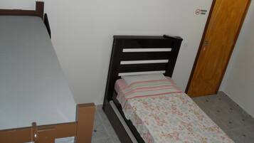 A small, single-bed room with a wooden headboard and a floral bedspread.