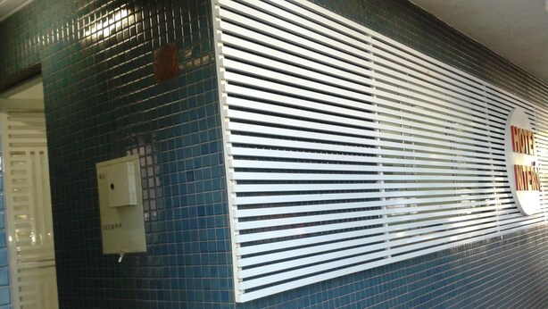 A blue-tiled wall with a white horizontal slat design and a logo. - Hotel Niterói (Cascavel)