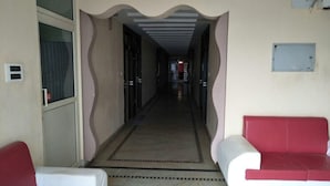A hallway with a patterned floor, two red and white sofas, and a door on the left.