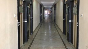 A long, narrow hallway with doors on both sides, a shiny floor, and a ceiling with recessed lighting.