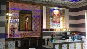 A room with a patterned wall, a decorative window, and a reception desk with a vase of flowers.
