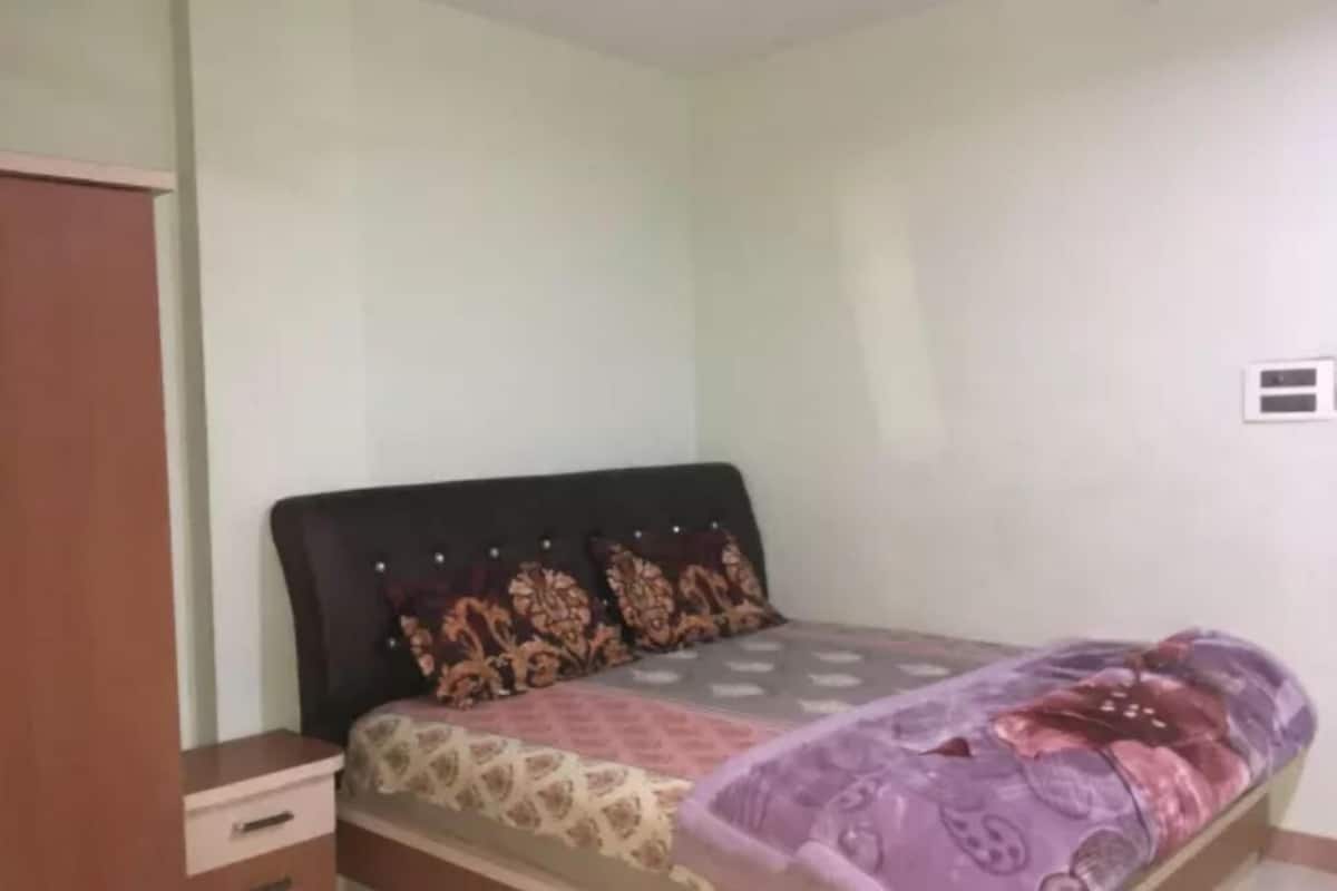 A bedroom with a bed, a nightstand, and a wardrobe.