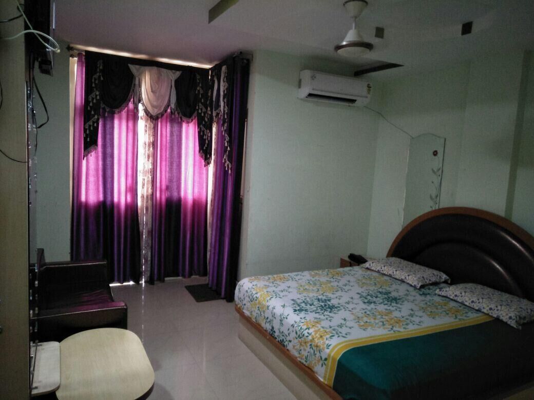 A bedroom with a bed, a chair, a desk, and an air conditioning unit.