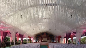 An indoor event space with rows of white-covered chairs facing a stage.