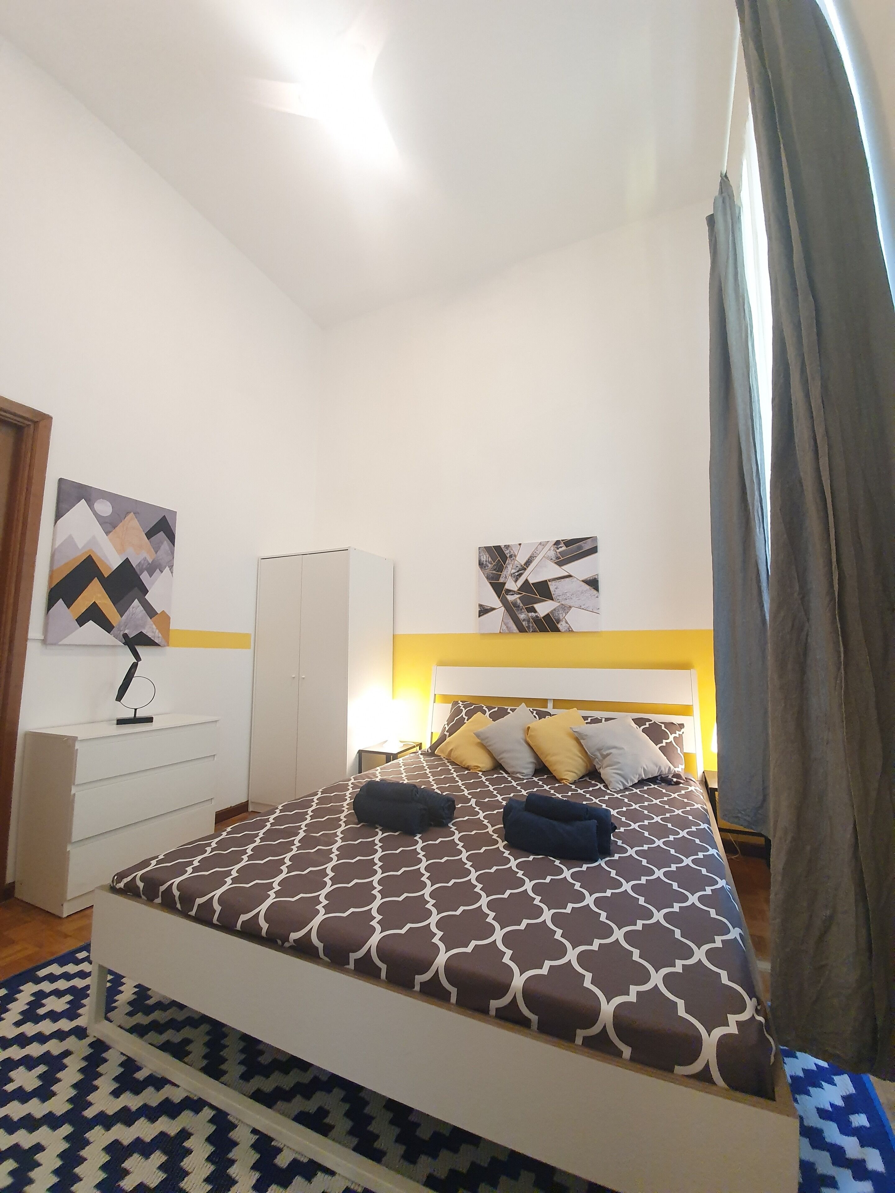 A bedroom with a bed, a wardrobe, a desk, and a chair.