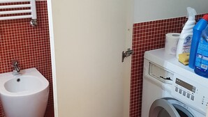 A compact bathroom with a washing machine, bidet, and a toilet. - Casa Maltese (Turin)