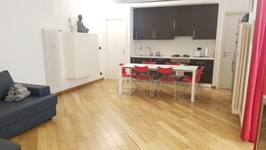 A compact living space with a dining area, kitchenette, and a sofa with rolled towels. - Casa Maltese (Turin)
