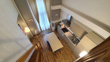 Una cocina compacta con comedor, piso de madera y una escalera que lleva a un nivel superior.