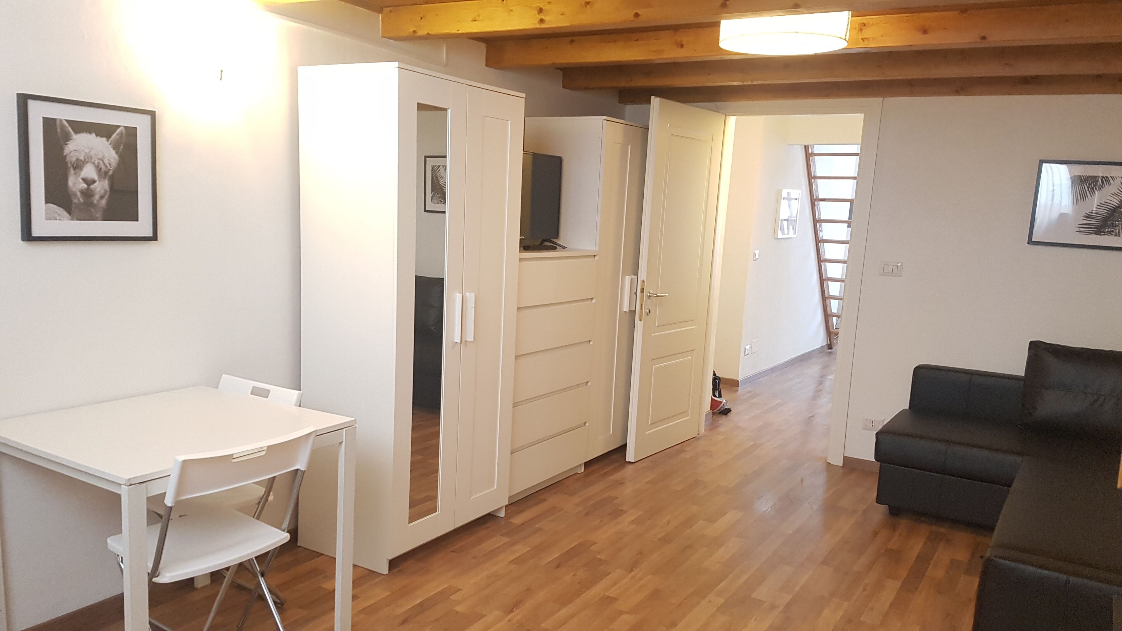 A compact living space with a dining table, a sofa, and a wardrobe.