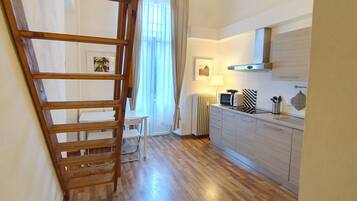 Una cocina amplia con piso de madera, estufa empotrada y ventana con cortinas.