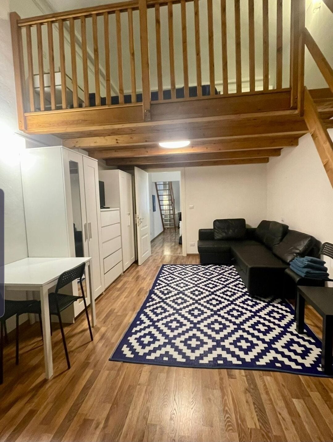 Un espace de vie compact comprenant un coin repas, un canapé et un tapis à motifs.