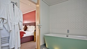Un baño moderno con una bañera verde, un lavabo blanco y una zona de ducha.