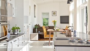 Una cocina moderna con comedor, un sofá y una televisión al fondo.
