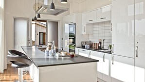 Una cocina moderna con armarios blancos, electrodomésticos de acero inoxidable y una isla central con taburetes de bar.