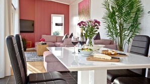 Un salon moderne avec une table blanche, deux canapés, une table basse et une grande plante.