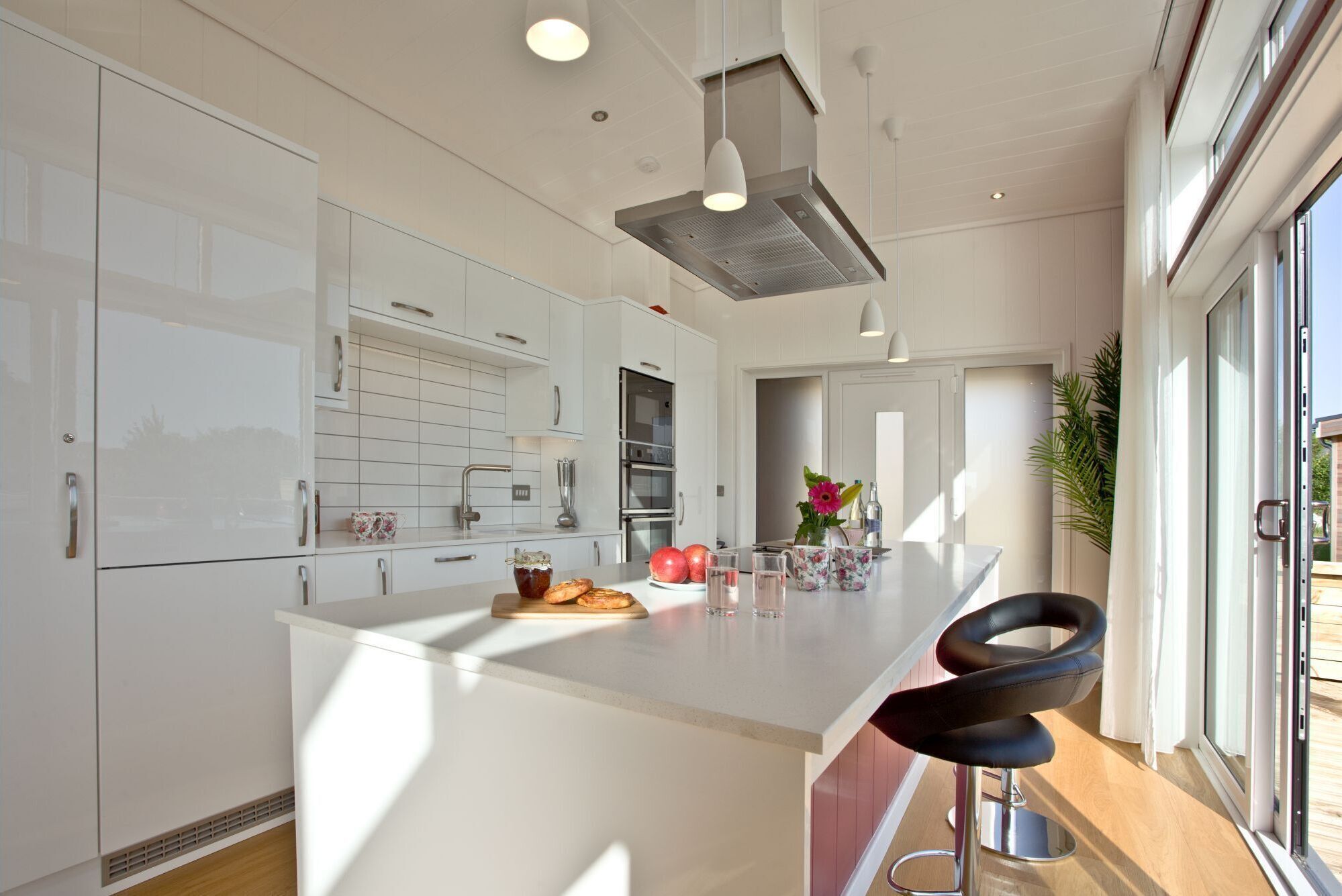 A modern kitchen with white cabinetry, a central island, and a bar area with stools.