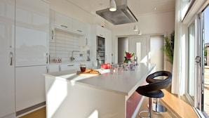 Une cuisine moderne avec des meubles blancs, un îlot central et un coin bar avec des tabourets.